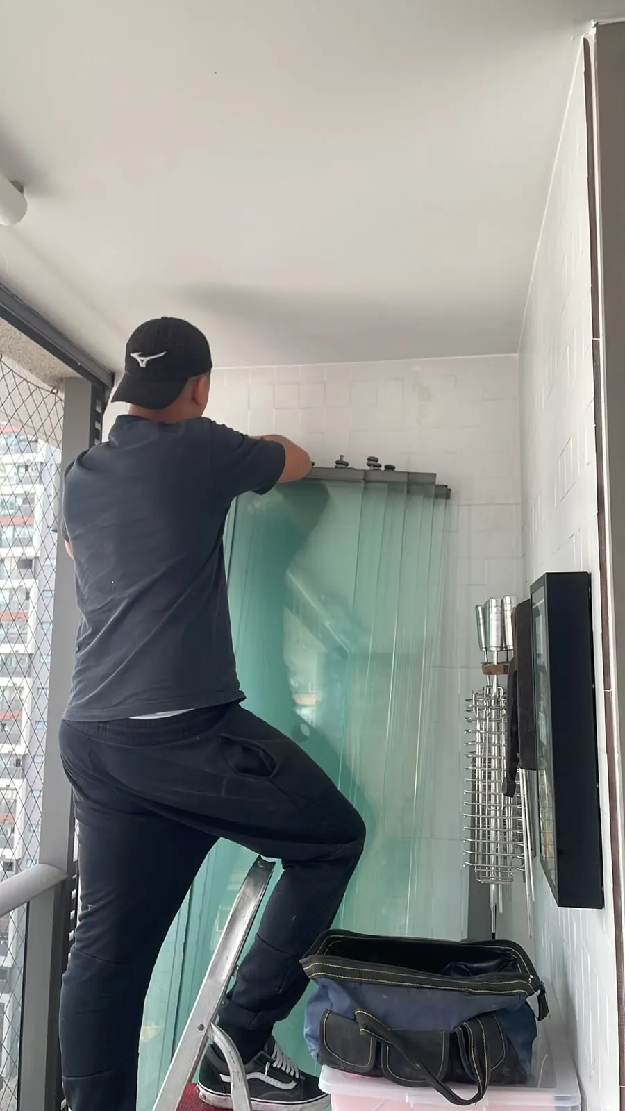 Técnico realizando manutenção no envidraçamento de uma sacada